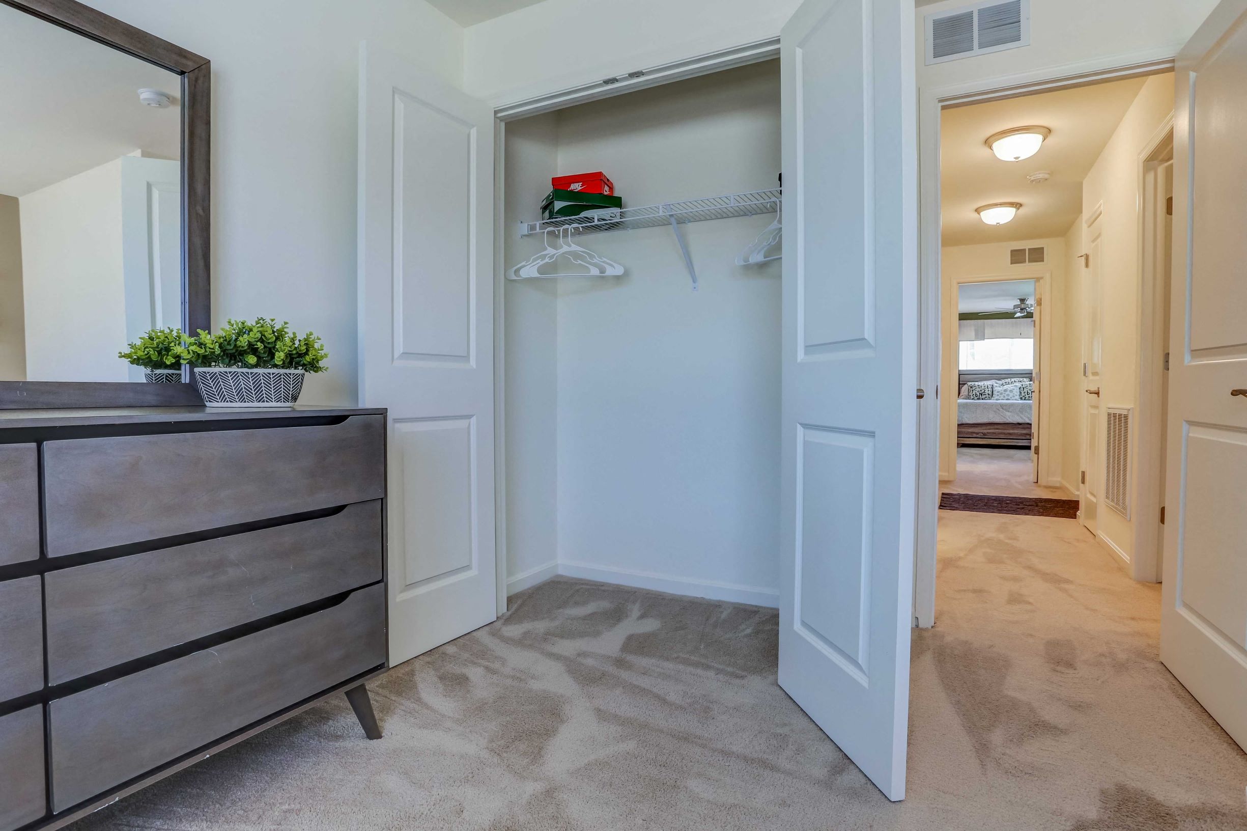 a hallway with a dresser and a closet with a mirror