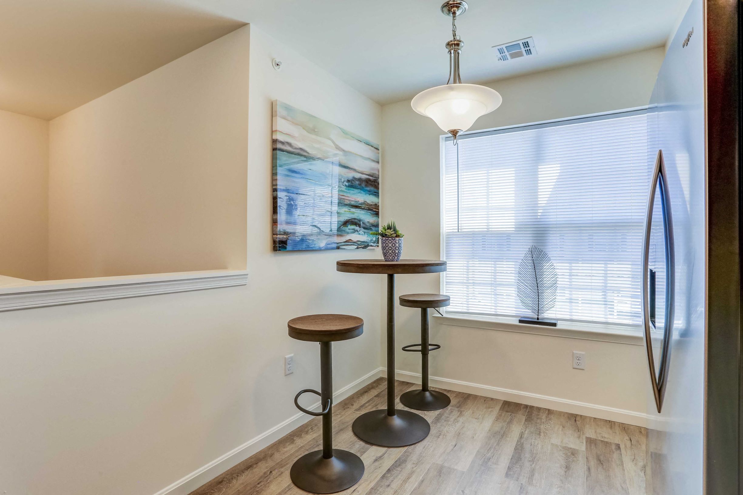 a bar area with stools next to a window and a refrigerator