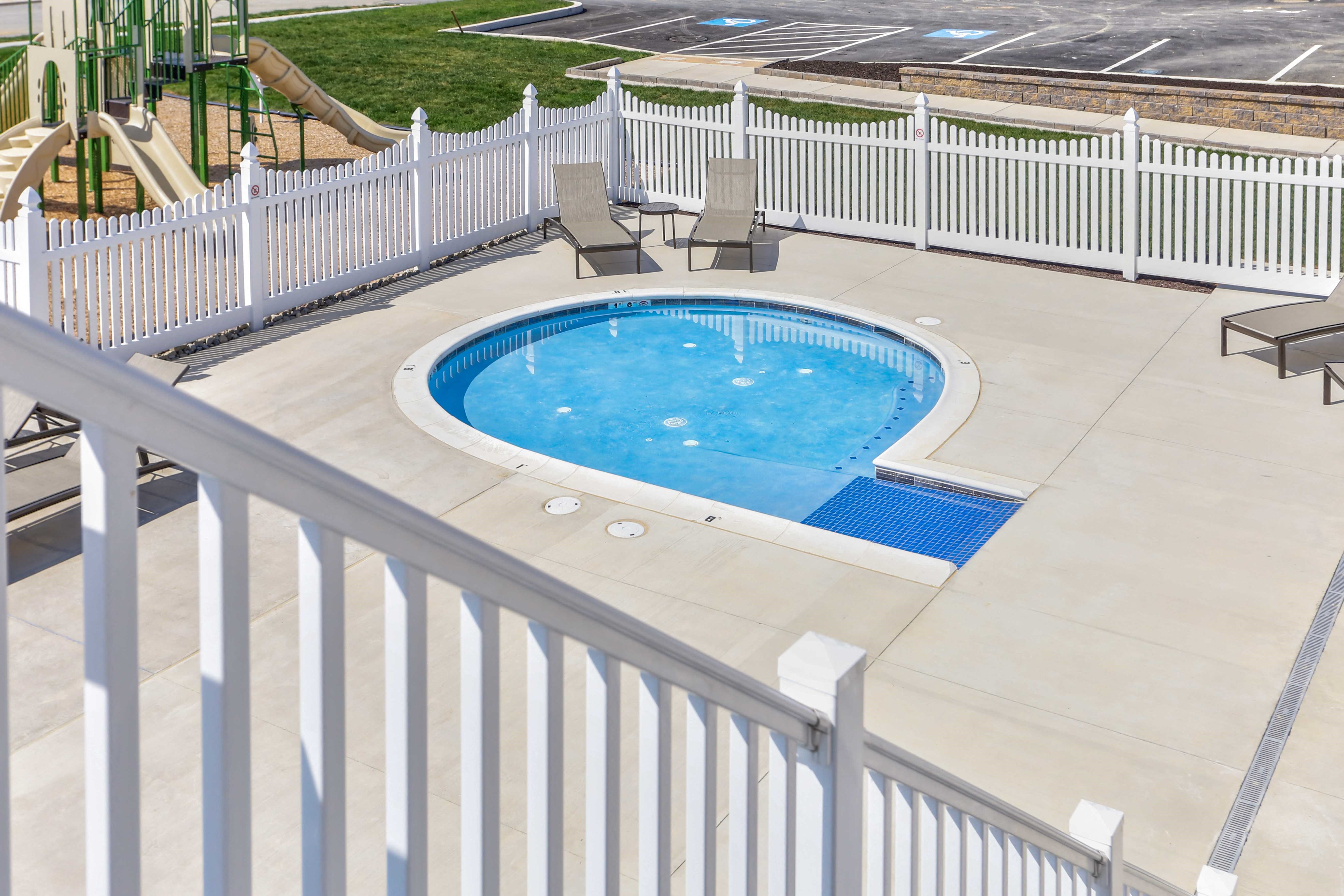 a swimming pool is shown in the middle of a fenced in yard with chairs
