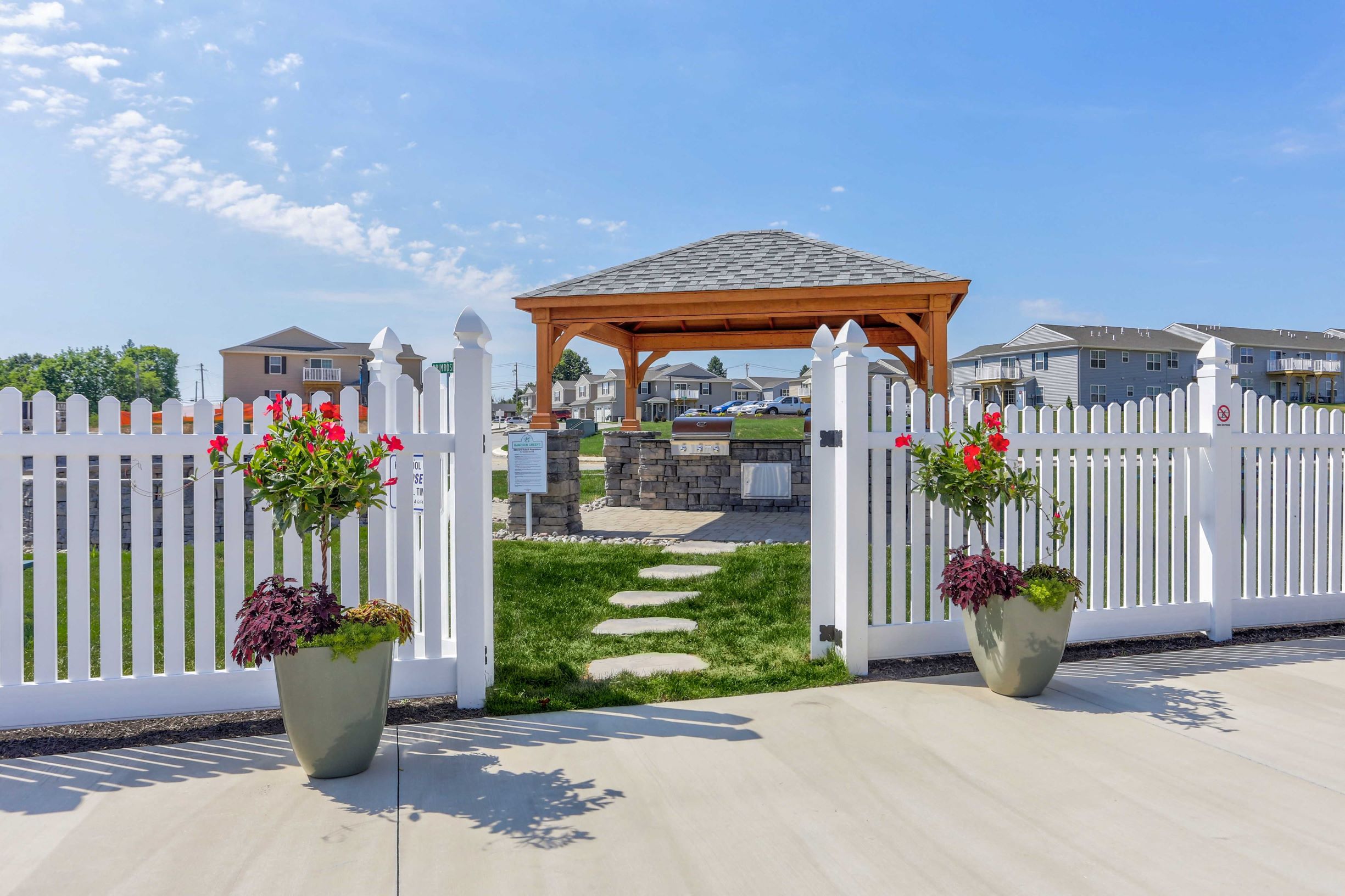 a white fence with a gazebo in front of a yard with flowers