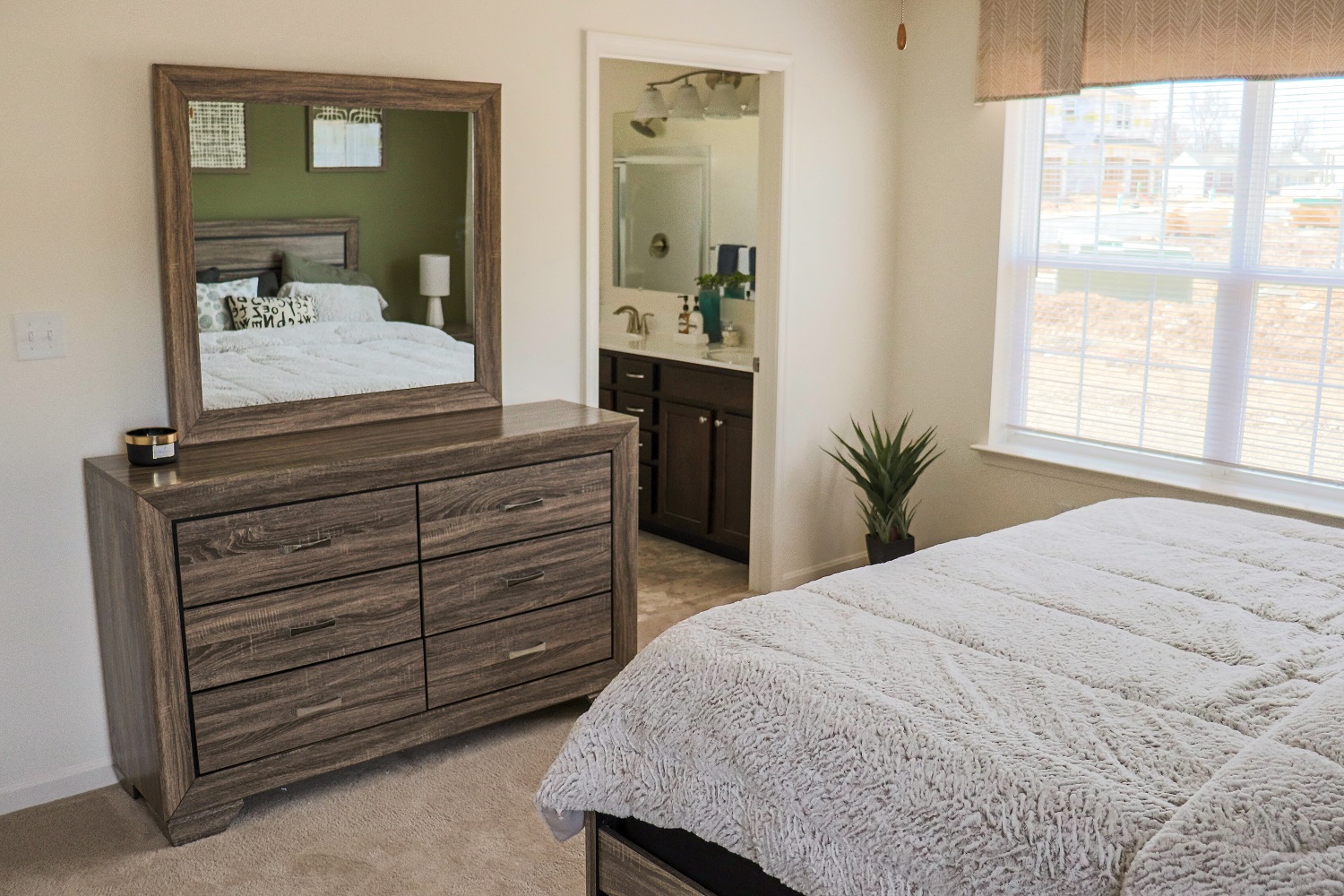 a bedroom with a bed and a mirror and a window