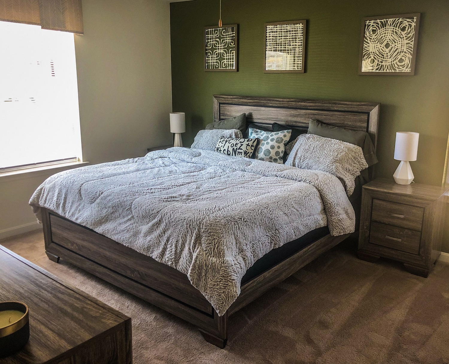 a bedroom with green walls and a bed with a blanket and pillows