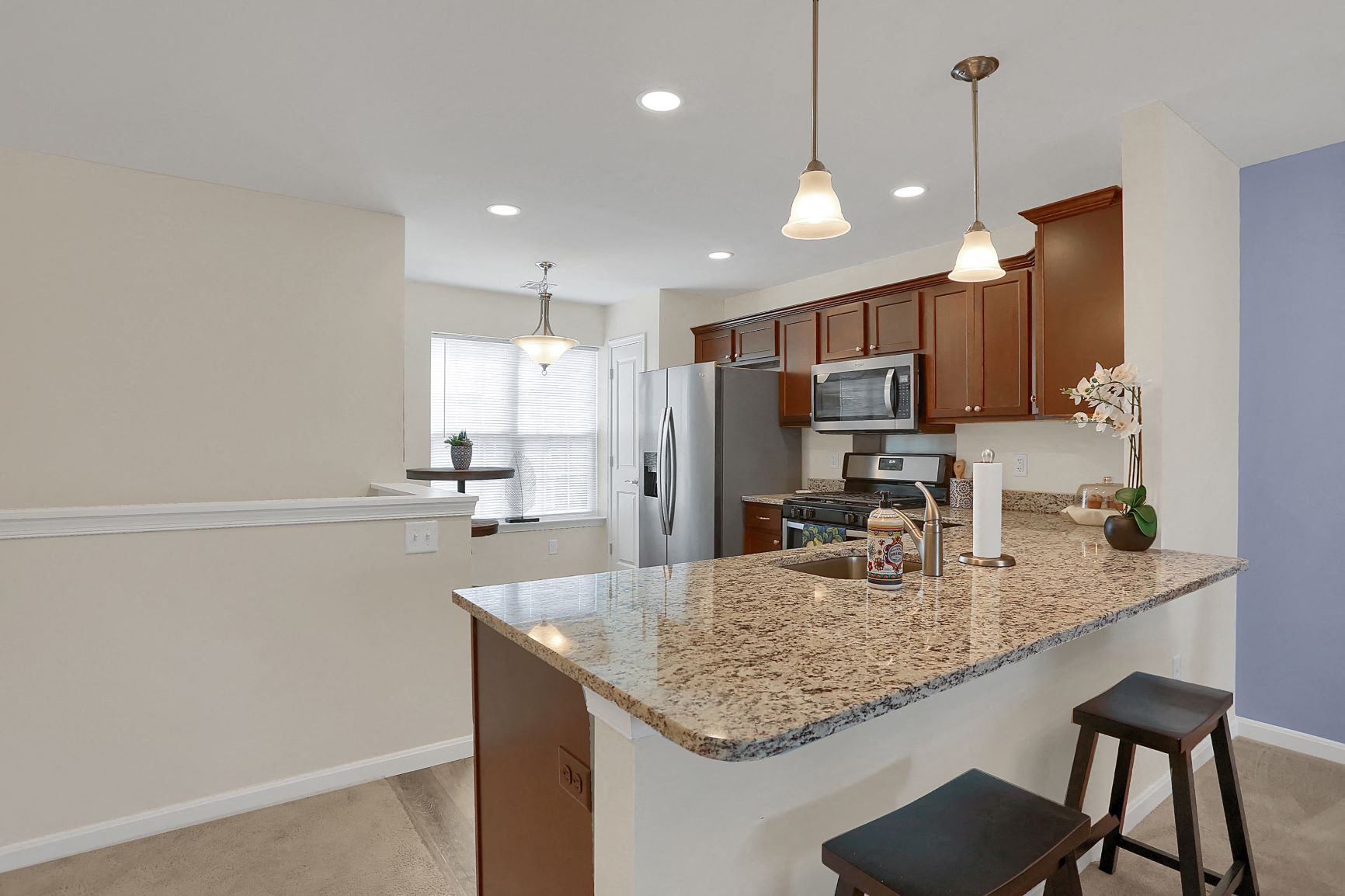a kitchen with a granite counter top and a stainless steel refrigerator