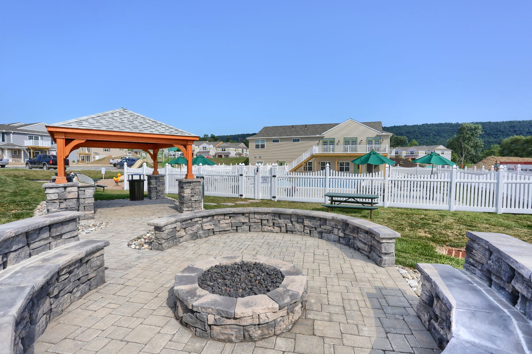 a stone patio with a fire pit and a pavilion