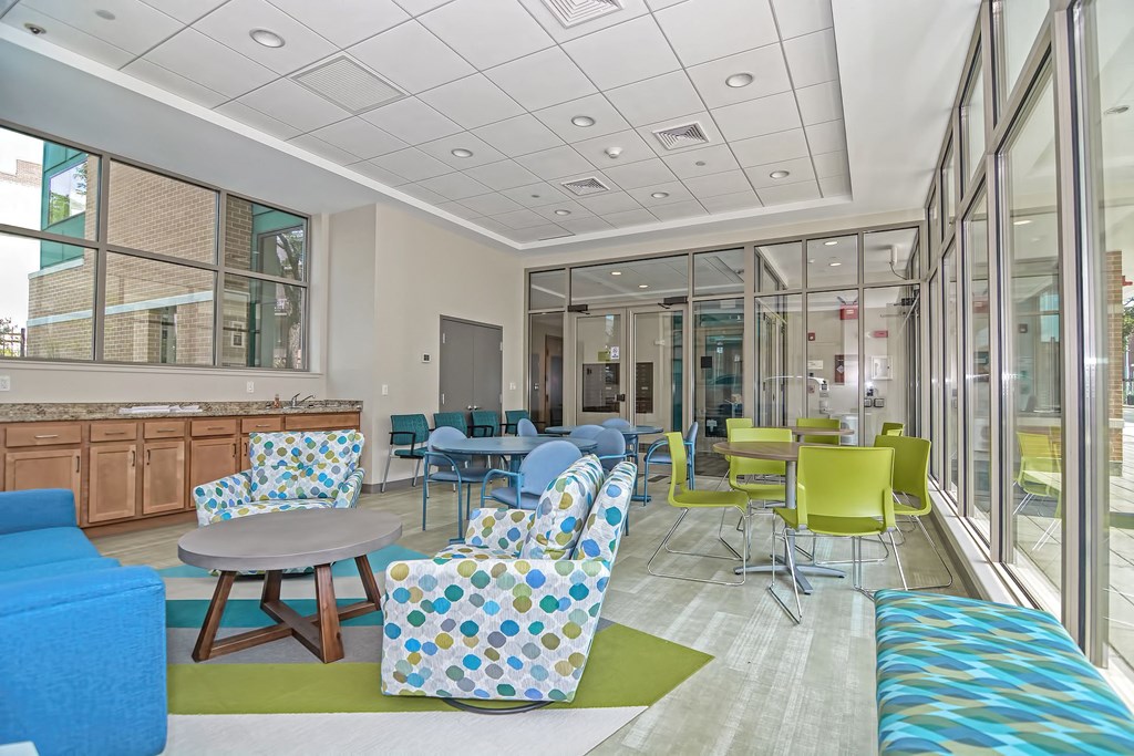 a lobby with colorful chairs and tables and windows