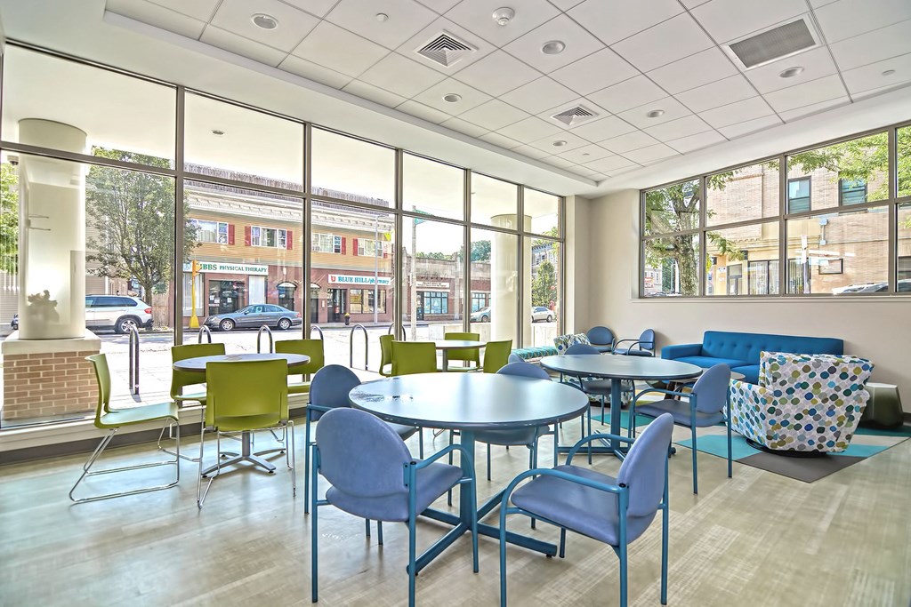 a lounge area with tables and chairs and large windows