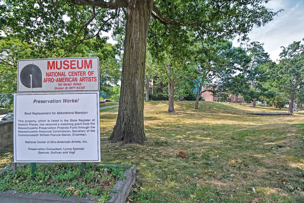 a sign in front of a museum in a park