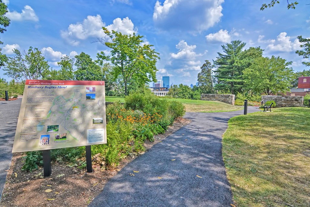a park with a sign and trees and a path