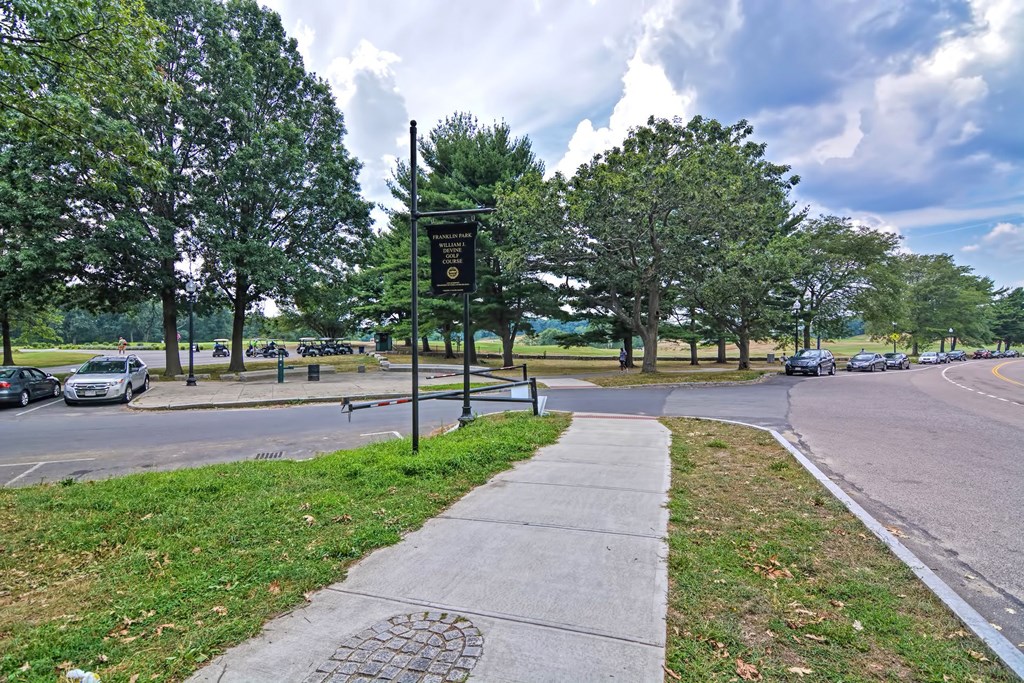 a sidewalk on the side of a street in a park