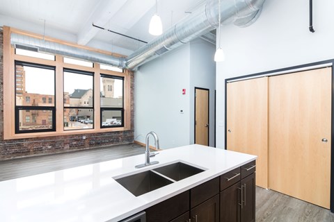 a kitchen with a large window and a white counter top and a sink
