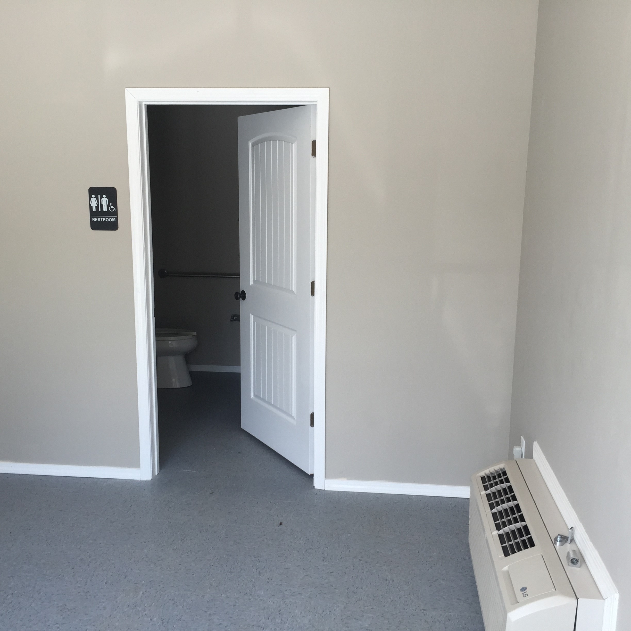 A white door is open to a small bathroom.
