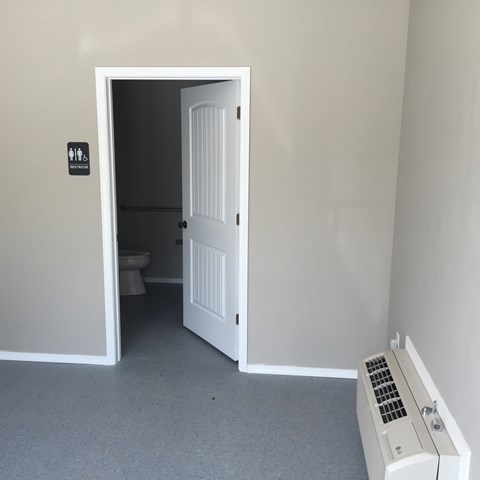 A white door is open to a small bathroom.
