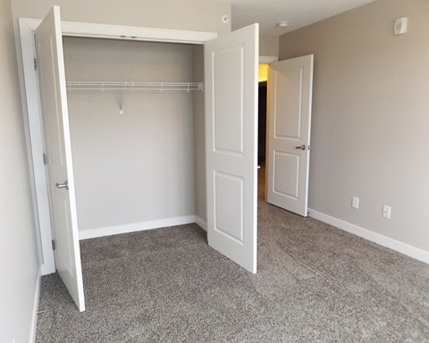 an empty bedroom with two closets and two doors