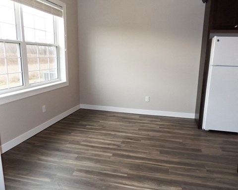 an empty room with wood floors and a refrigerator
