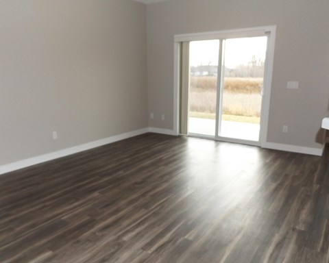 an empty living room with wood floors and a sliding glass door