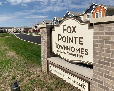 a sign for fox point townhomes in front of a row of houses