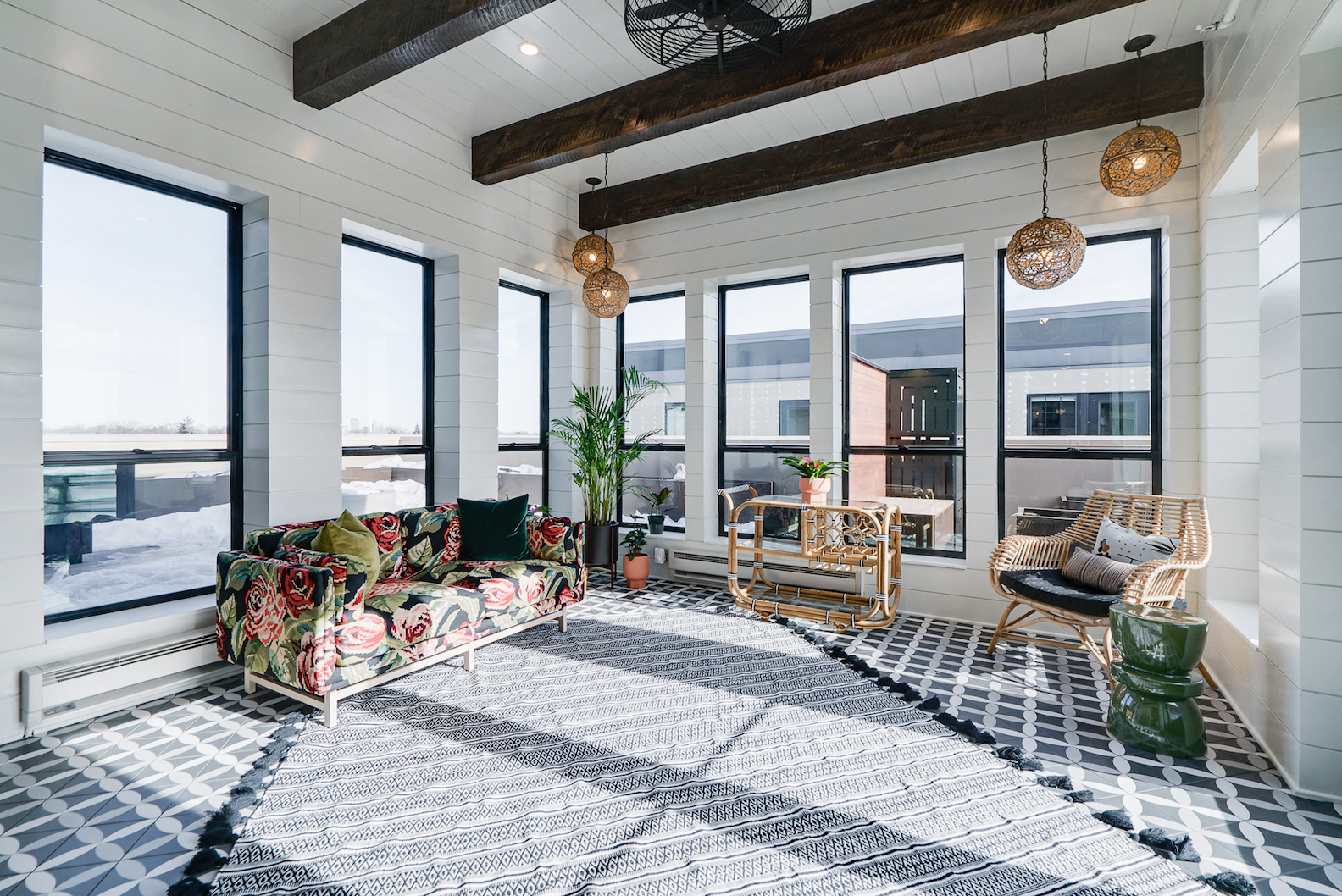 a living room with a couch and chairs and large windows