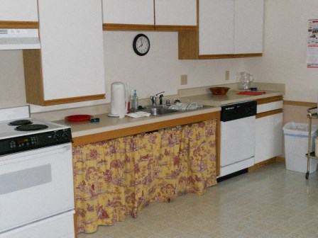 a kitchen with white appliances and a yellow curtain on the counters