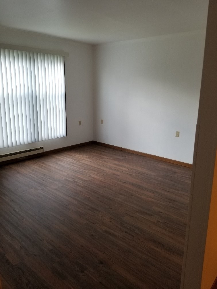 an empty living room with wood floors and a window