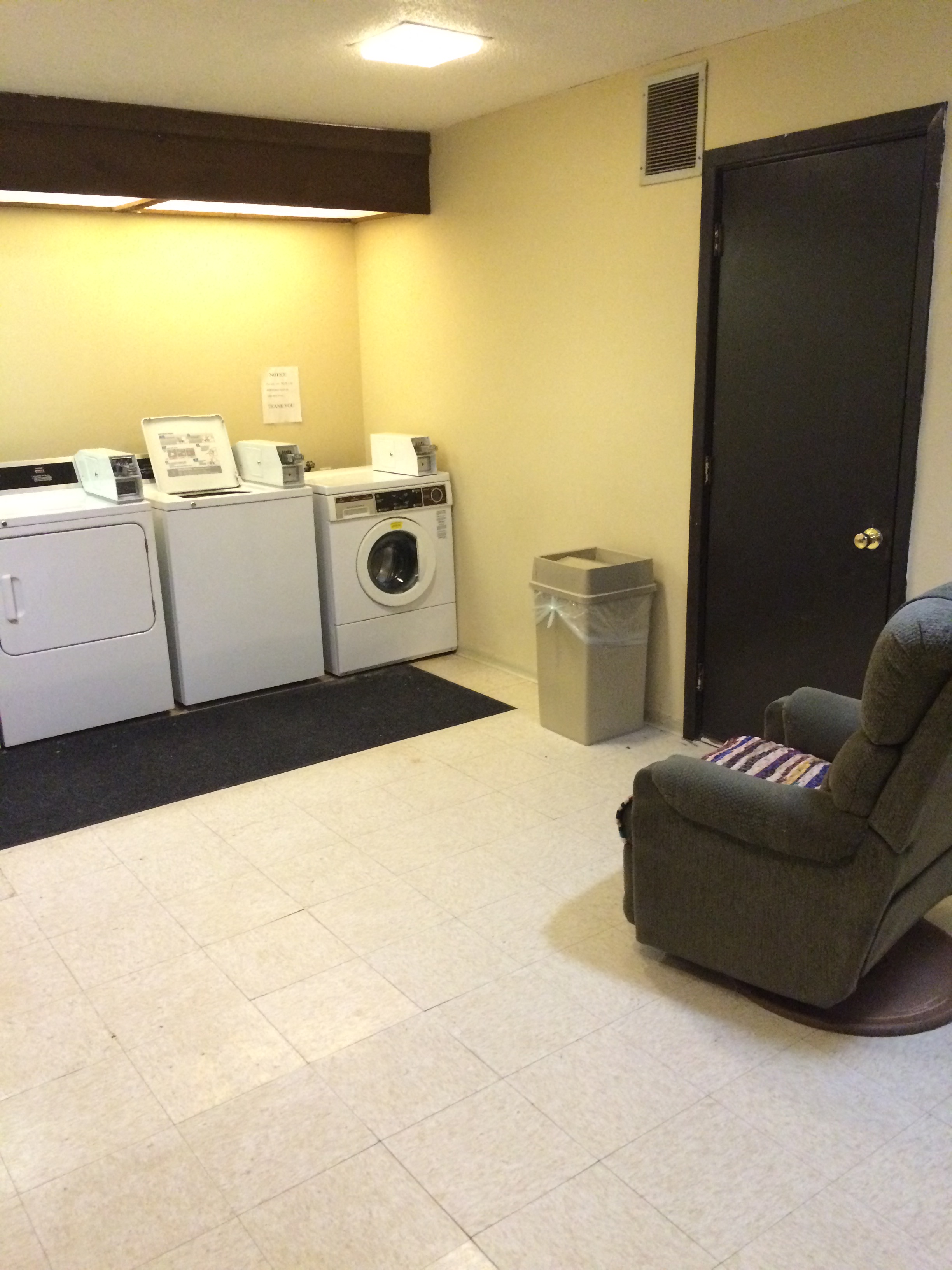 a laundry room with washing machines and a chair