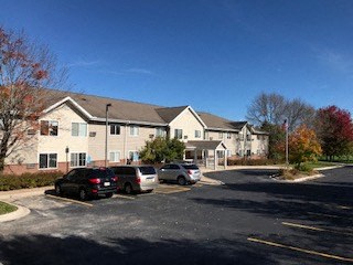 A parking lot in front of a building with cars parked.