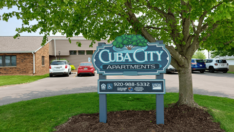 A sign for Cub City Apartments is displayed in front of a tree.