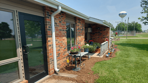 A brick house with a black door and a white pipe on the side.