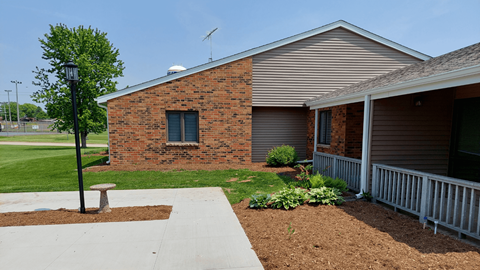A brick house with a white fence and a tree in front.