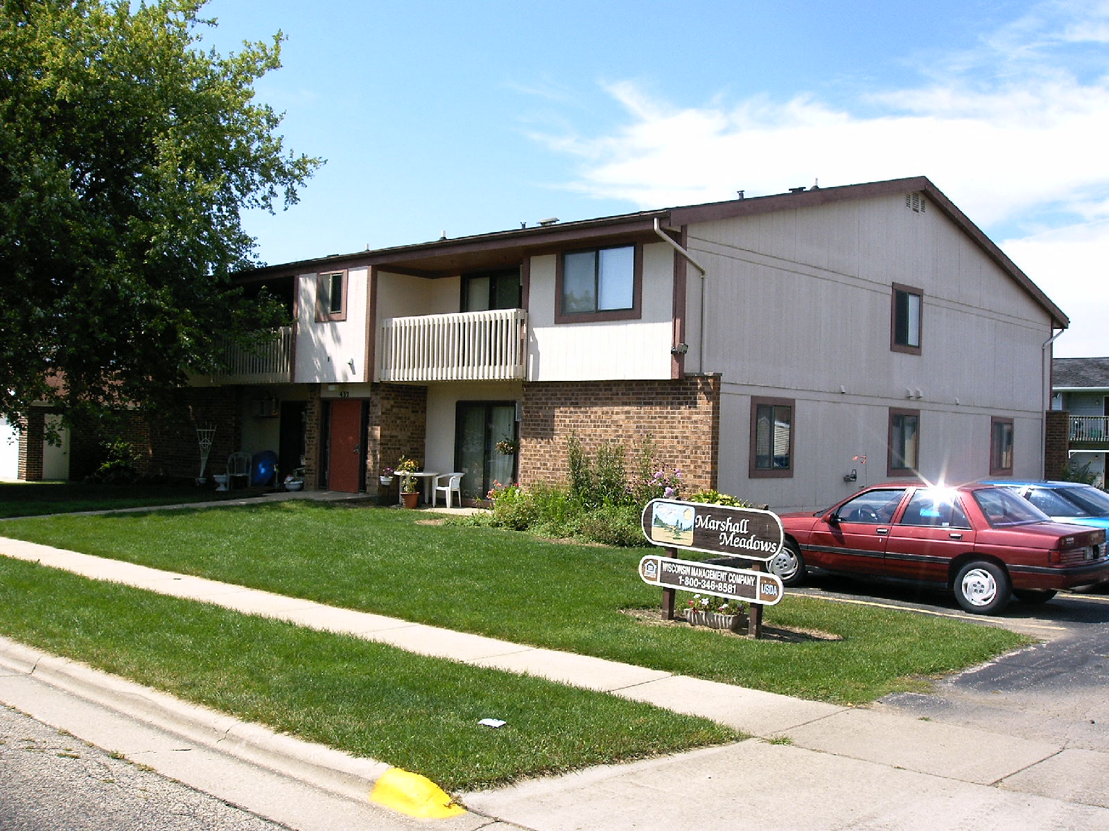 an apartment building with a red car parked in front of it
