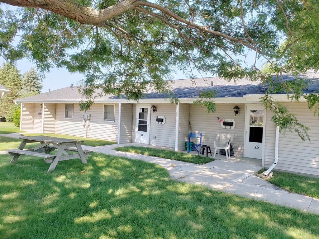 a small white house with a picnic table in the yard