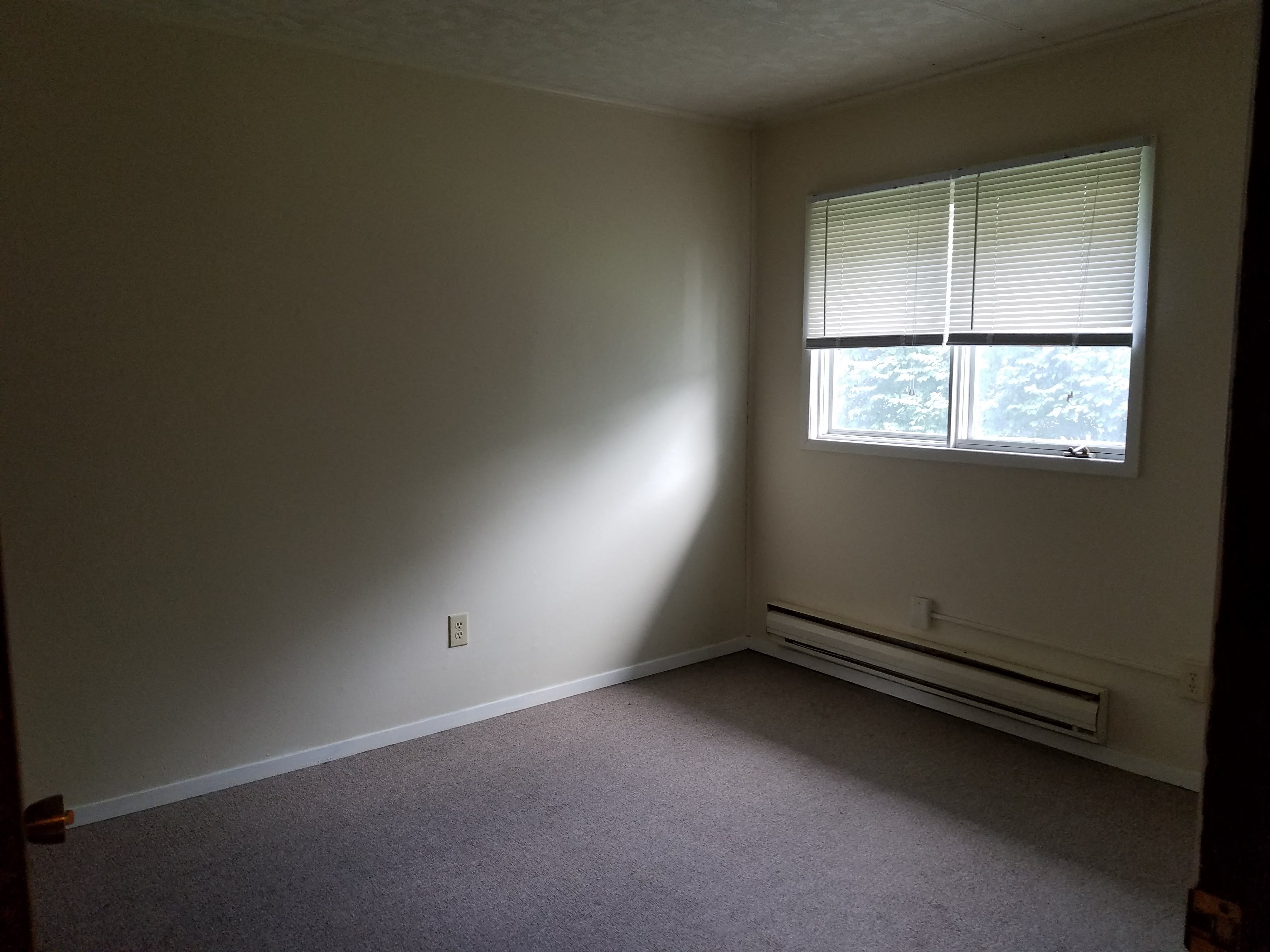 an empty room with a window and a carpet