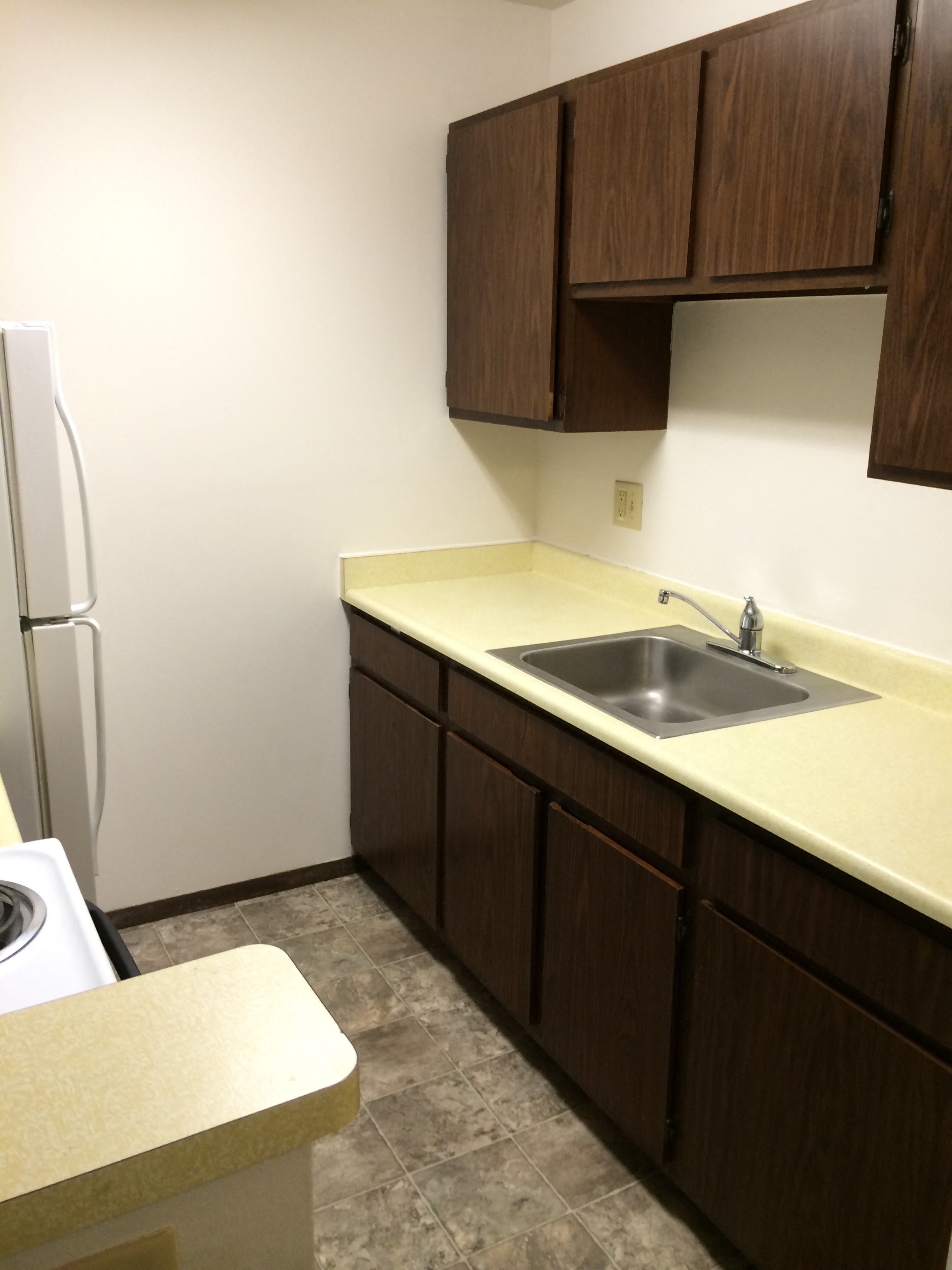A kitchen with brown cabinets and a white fridge.