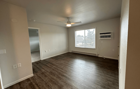 an empty living room with wood floors and a ceiling fan
