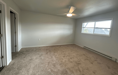 an empty living room with carpet and a window