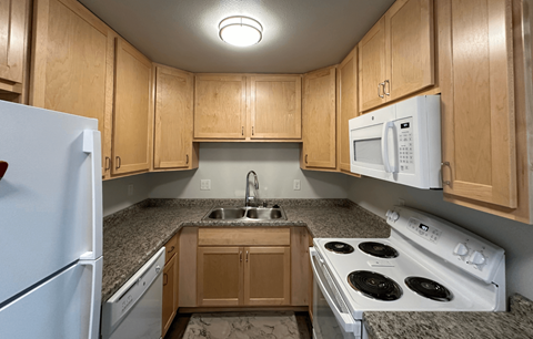 a kitchen with white appliances and granite counter tops and wooden cabinets