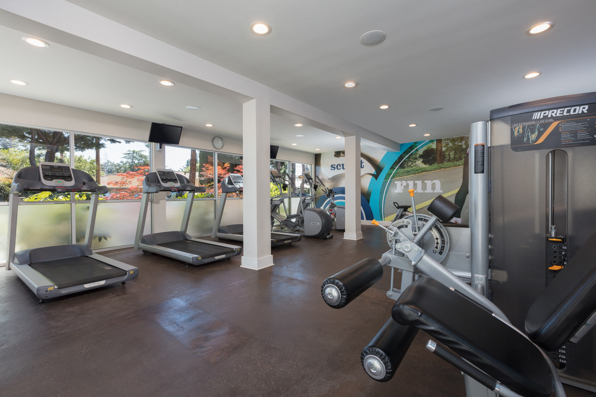 a gym with treadmills and other exercise equipment in a building with a window