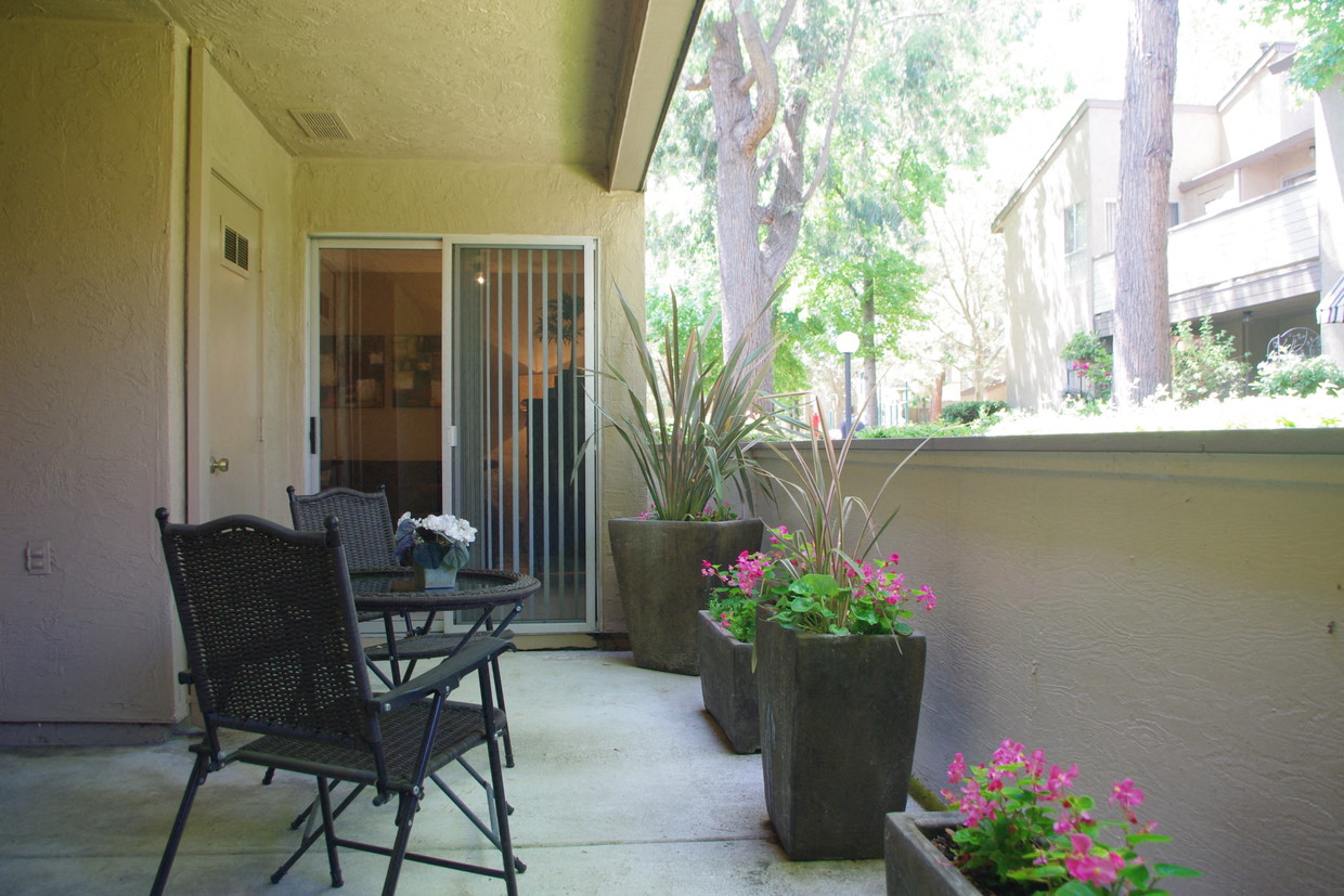 a patio with a table and chairs and potted plants