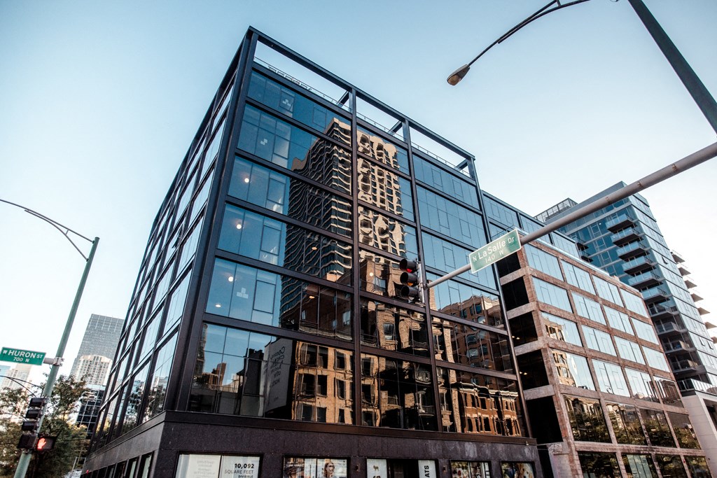 a tall glass building with a reflection of the empire state building