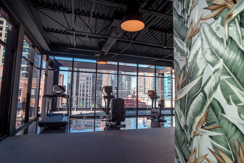 a gym with a view of the city and a large wall of windows