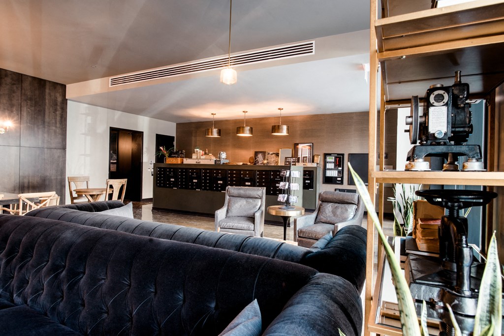 a living room with a black couch and a kitchen in the background
