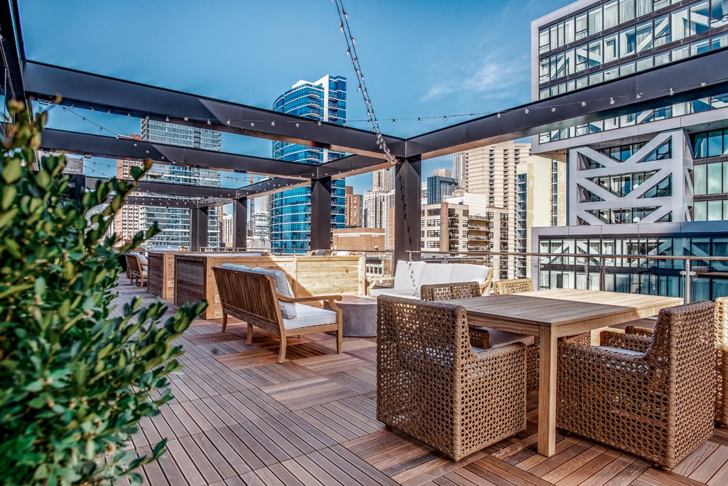 a rooftop terrace with tables and chairs and a city in the background