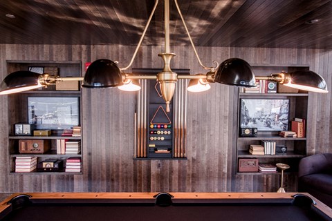 a pool table and lights in a room with wooden walls
