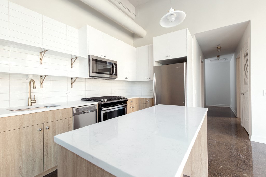 a white kitchen with stainless steel appliances and white countertops