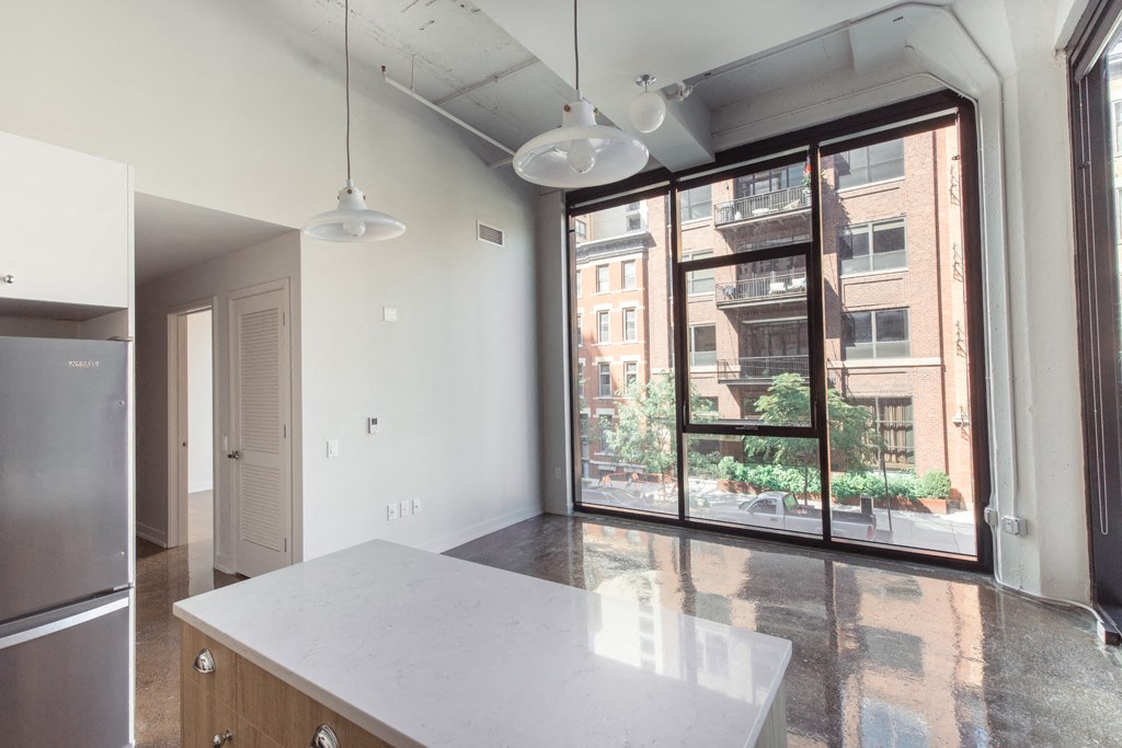 an empty kitchen with a large window and a white counter top