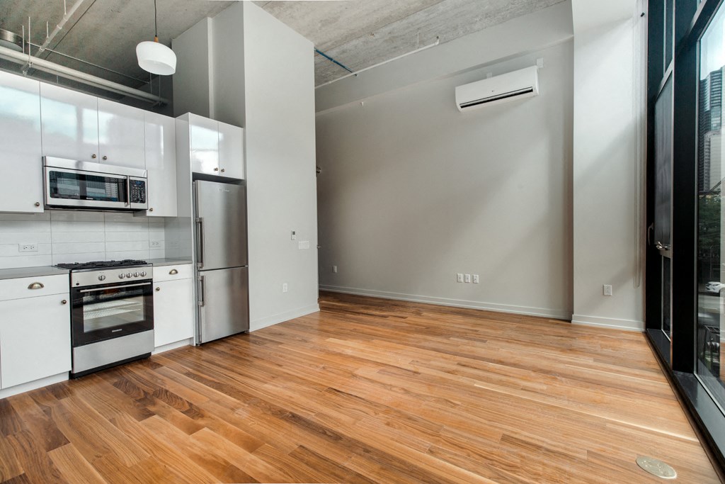 an empty kitchen with white appliances and a wood floor