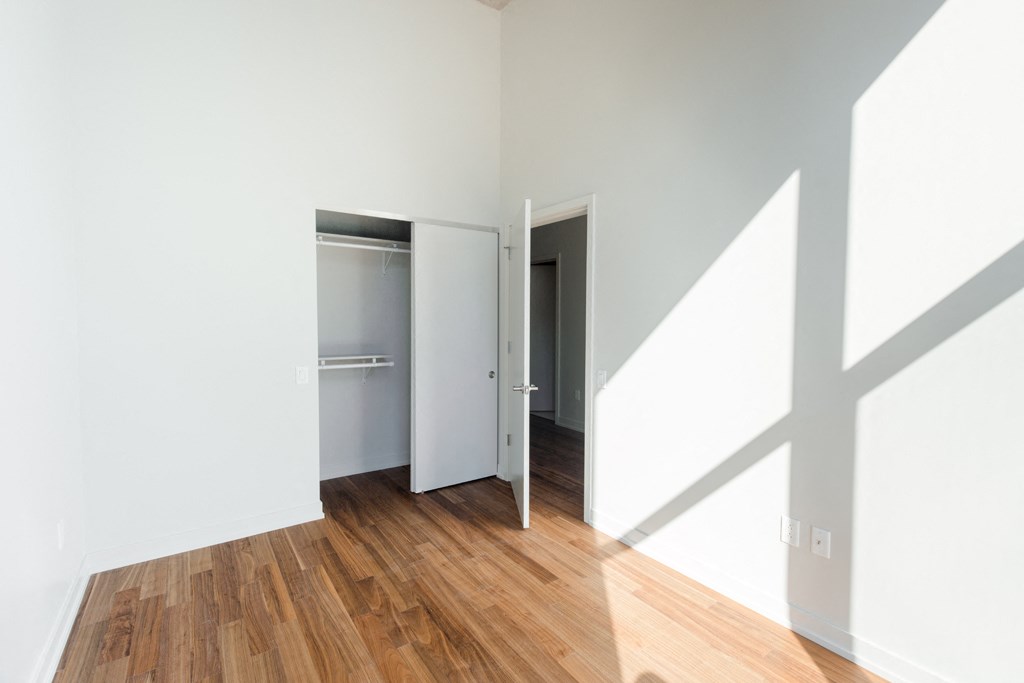 an empty room with white walls and wooden floors and a closet