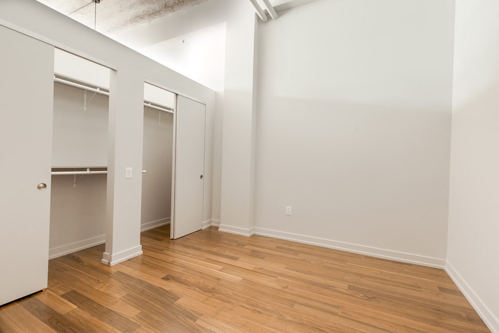 an empty room with wood flooring and a closet