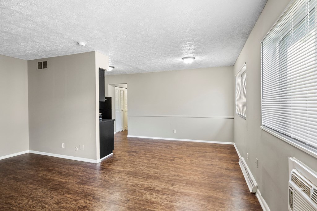 an empty living room with a hard wood floor and a window