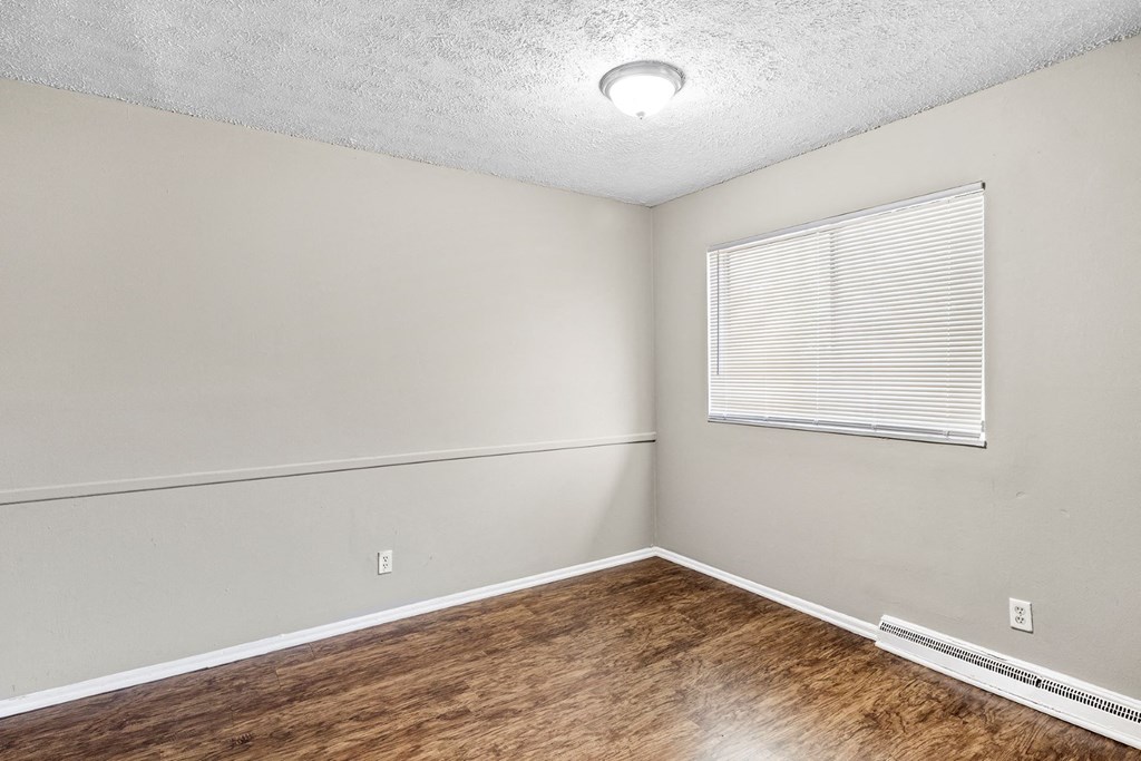 an empty room with a window and wood flooring