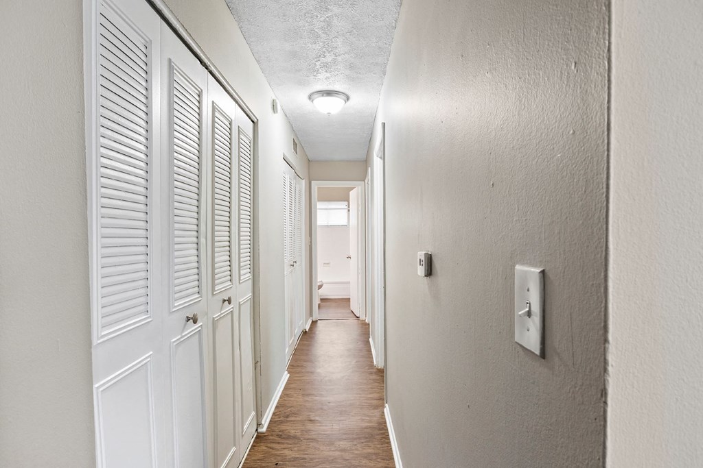a hallway with white shuttered doors and a light on the ceiling